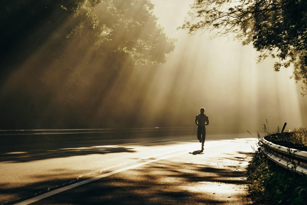 A runner on a road with dappled light