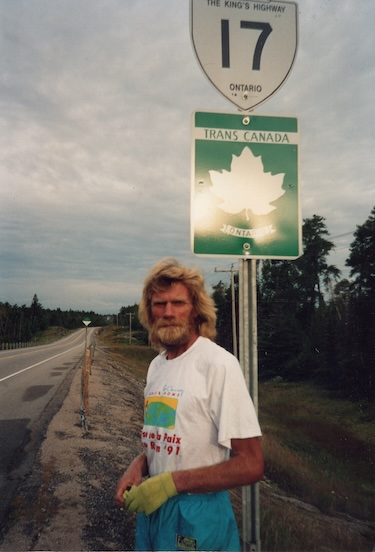 During his TransCanada Run, Al Howie standing beside a sign for Hwy 17, King's Highway in Ontario past Thunder Bay.