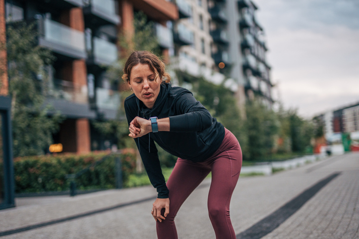 Runner on a city street, looking at her watch.